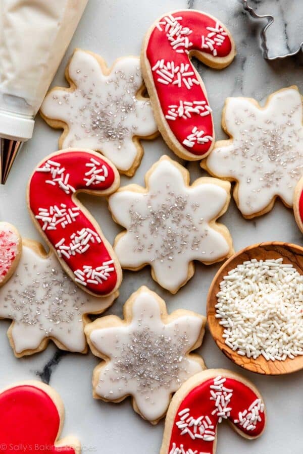 candy cane-shaped sugar cookies decorated with white sprinkles and snowflake-shaped cookies with white icing.