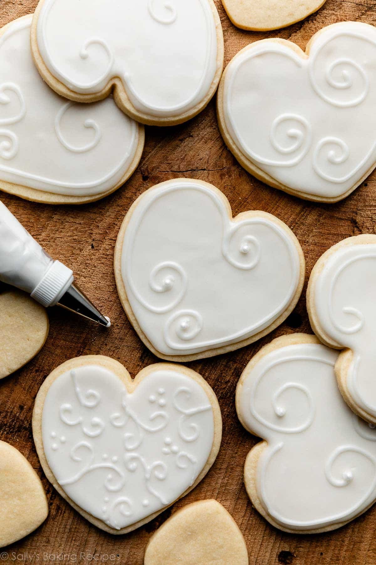 heart-shaped sugar cookies with white decorated icing on top.