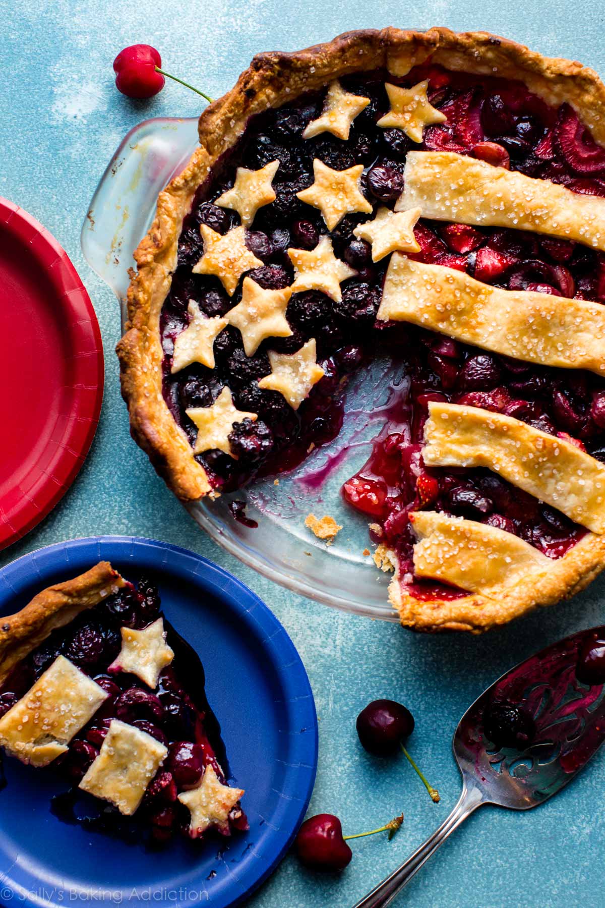 4th of July American flag pie dessert with a slice removed and placed on a blue plate.