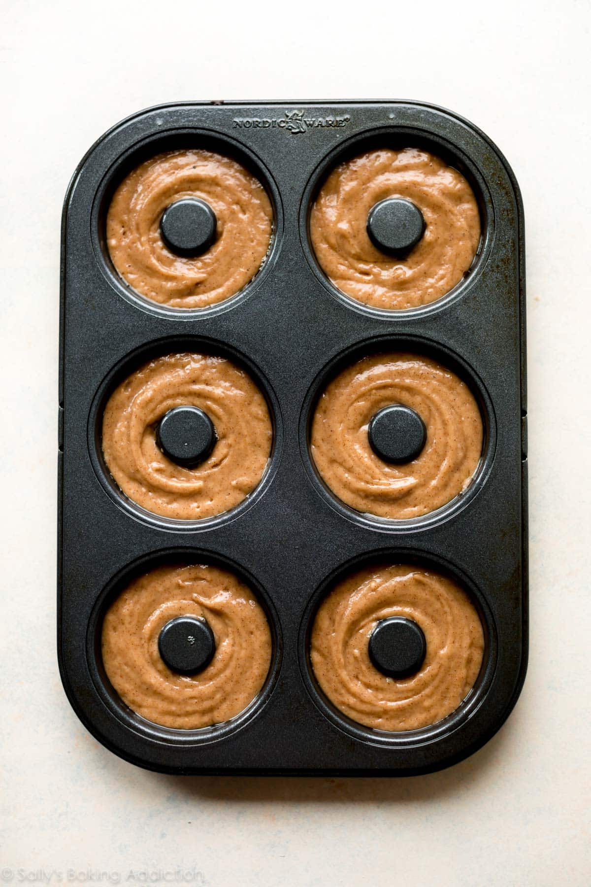 apple cider donut batter in a donut pan before baking