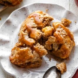 apple cinnamon scone on plate with caramel sauce on top.