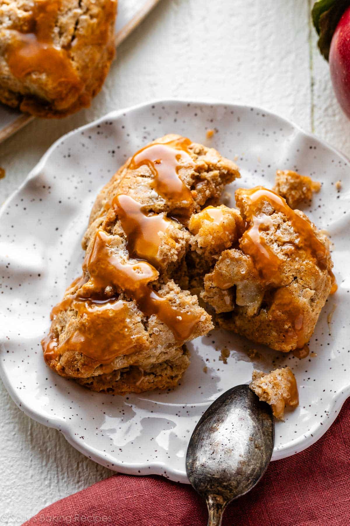 apple cinnamon scone on plate with caramel sauce on top.