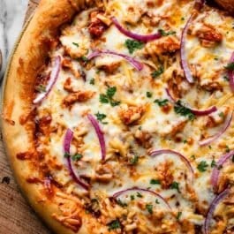 BBQ chicken pizza on wooden cutting board.