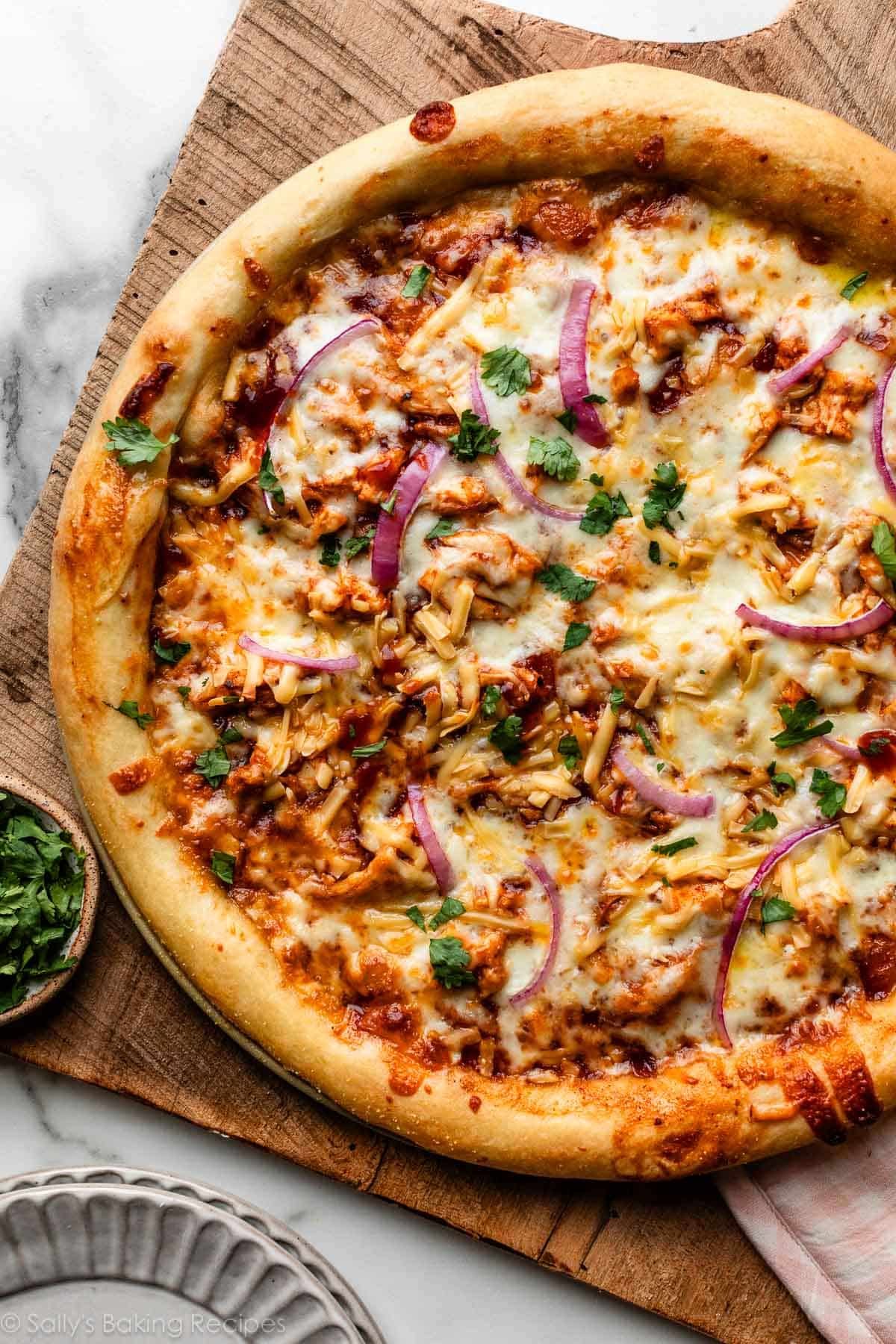 BBQ chicken pizza on wooden cutting board.