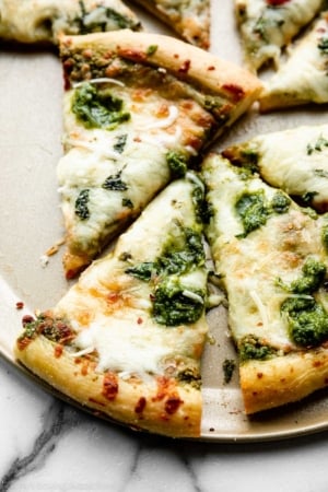 slices of pesto pizza made with mozzarella cheese and fresh pesto on top.