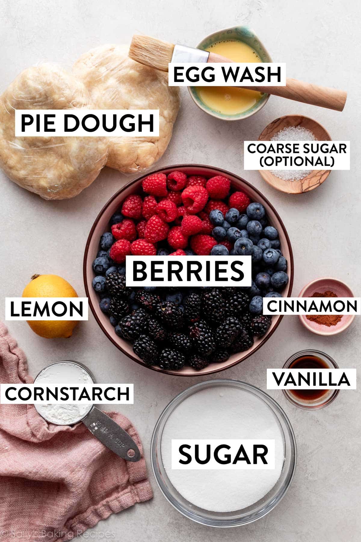 ingredients on counter including berries, egg wash, lemon, sugar, cornstarch, and cinnamon.