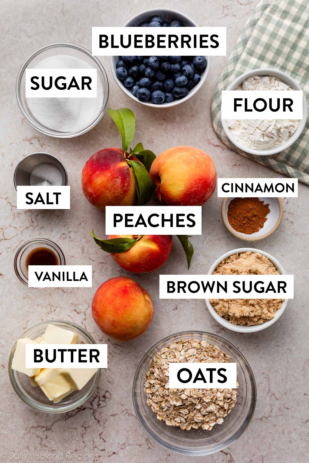 ingredients on counter including peaches, salt, sugar, flour, cinnamon, brown sugar, butter, and oats.