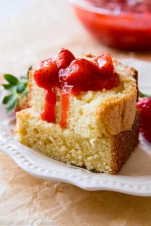 2 slices of brown butter pound cake on a white plate topped with strawberry compote