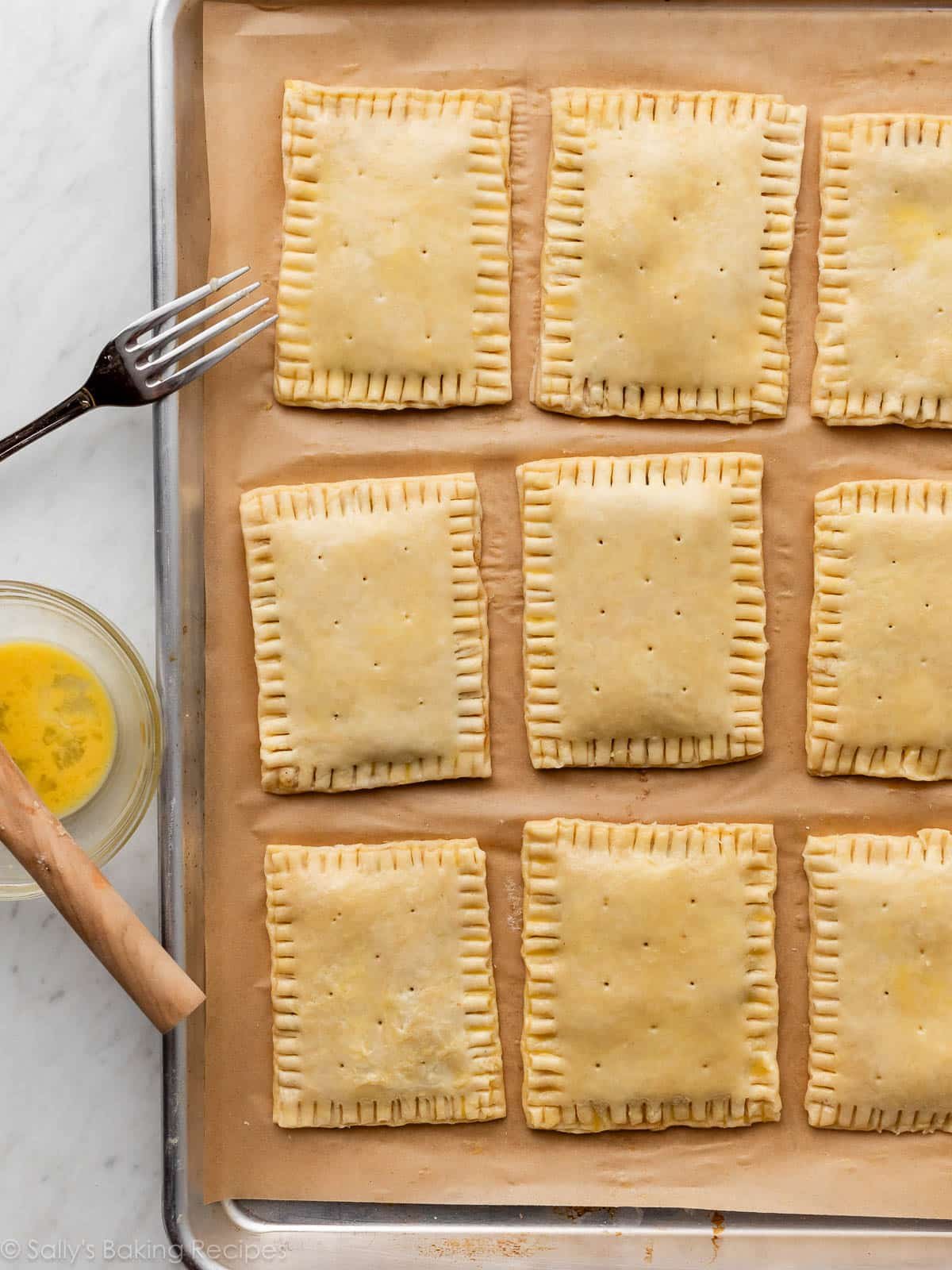 pastry tarts on lined baking sheet with crimped edges and holes poked into the tops.