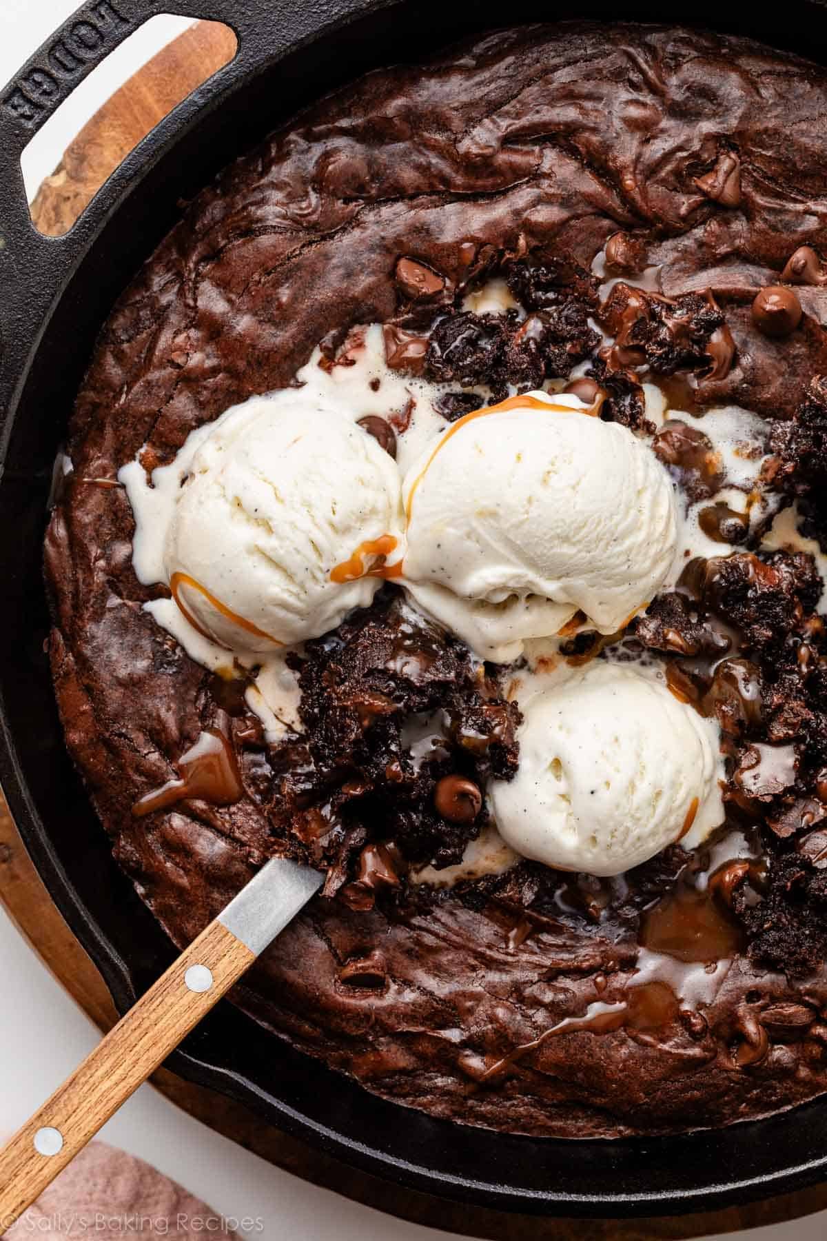 skillet brownie in cast iron skillet with vanilla ice cream.