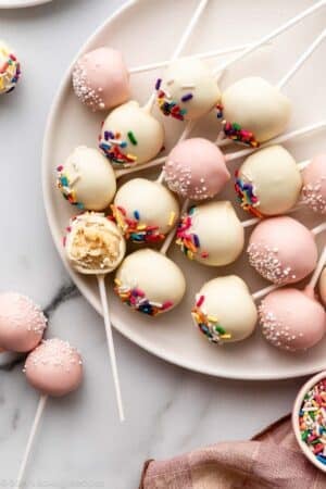 vanilla cake pops with sprinkles on plate.