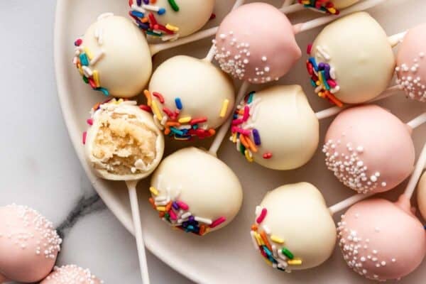 vanilla cake pops with sprinkles on plate.