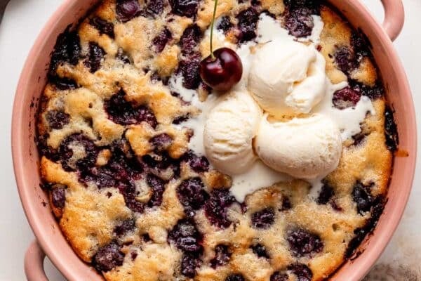 cherry cobbler in pink ceramic baking dish.