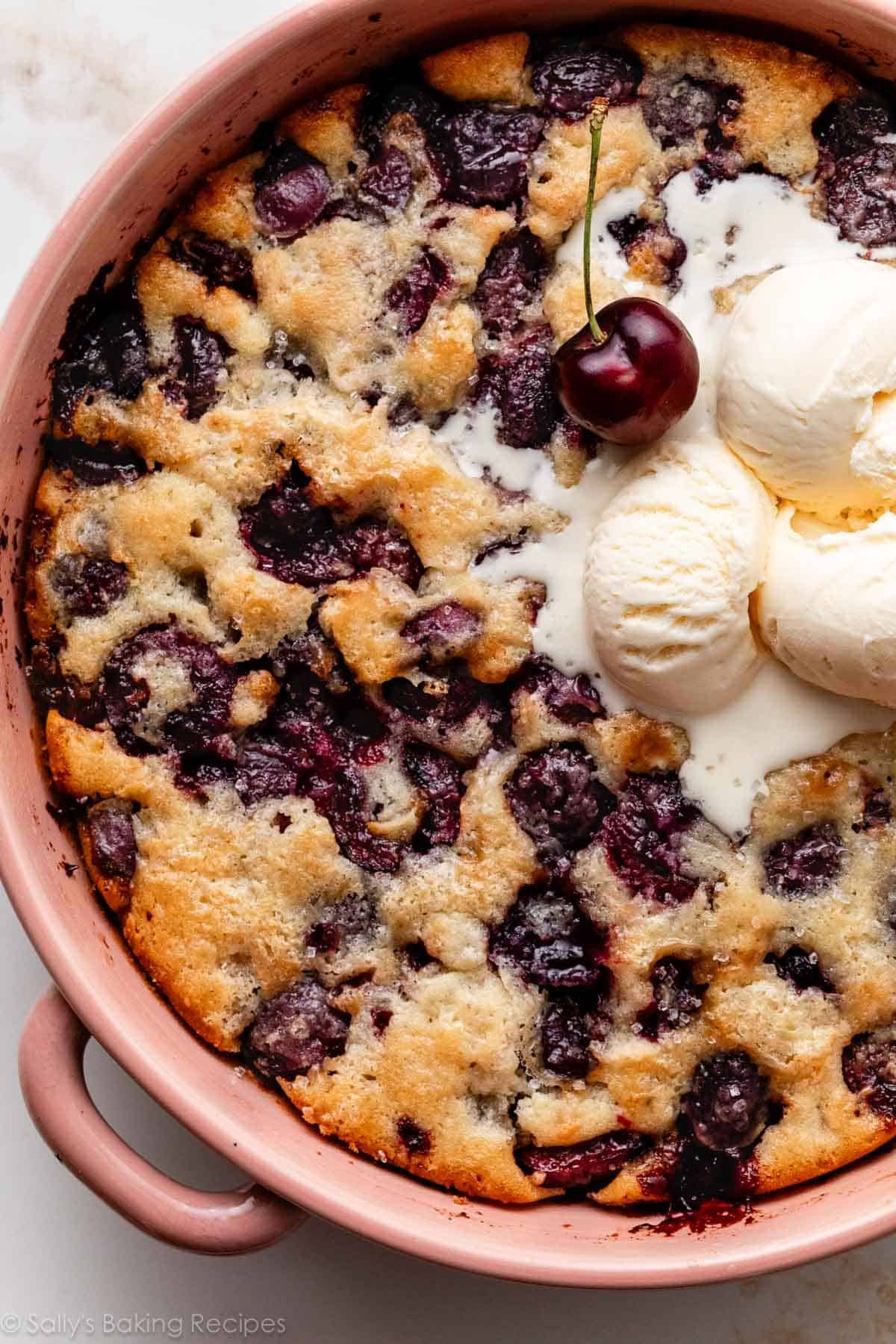 cherry cobbler in pink ceramic baking dish.