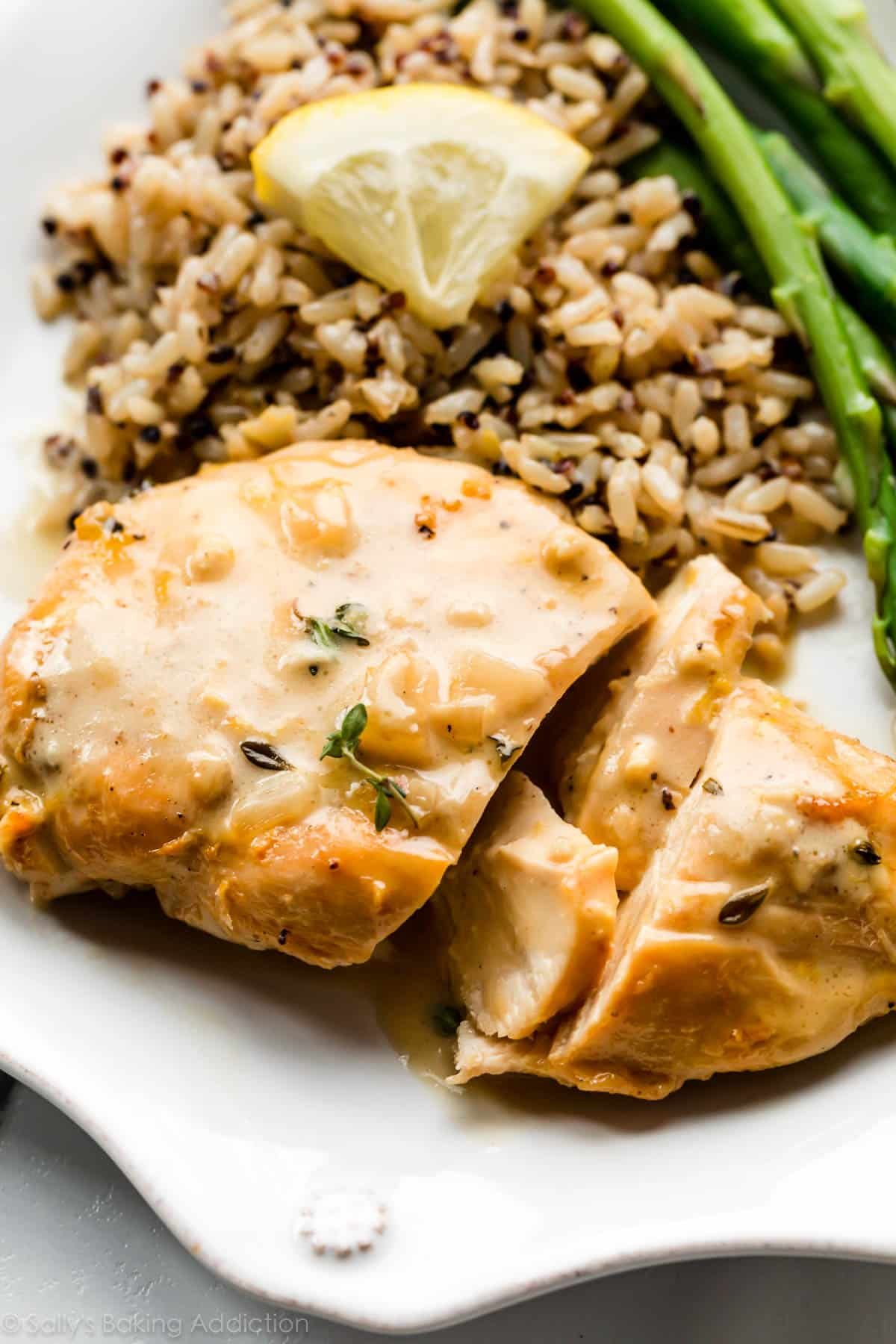 chicken breast with lemon and herbs on plate with rice and asparagus