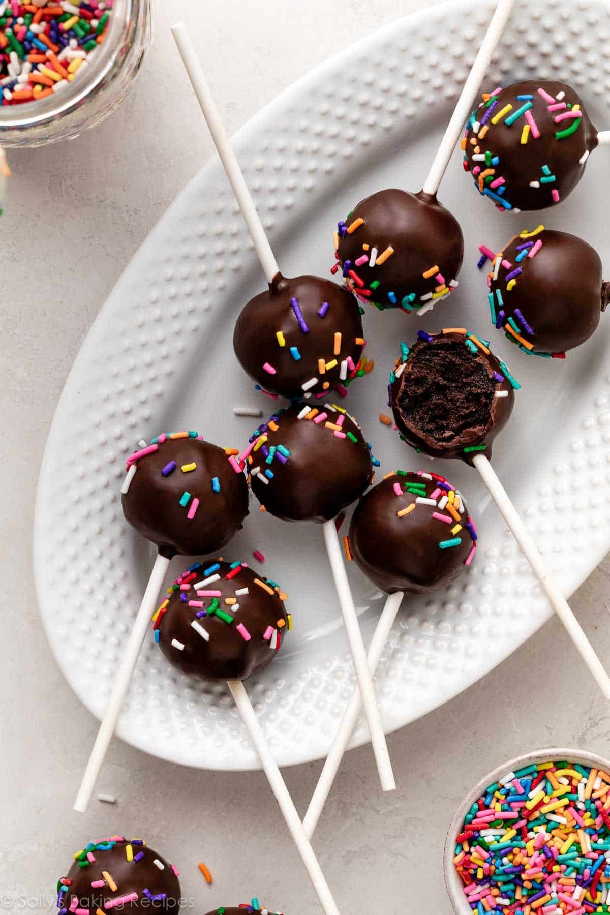 chocolate cake pops dipped in chocolate on white plate.