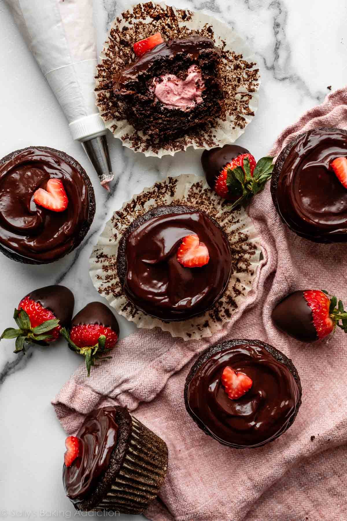 overhead image of chocolate covered strawberry cupcakes on a marble counter with pink linen.