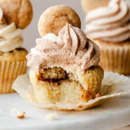 snickerdoodle cinnamon-swirled cupcake with bite taken out on marble cake stand.