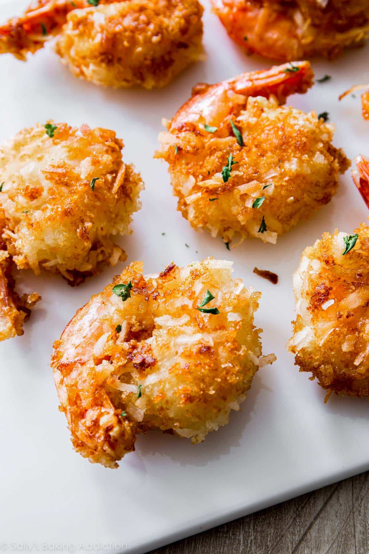 close-up of 6 coconut shrimp on white cutting board.