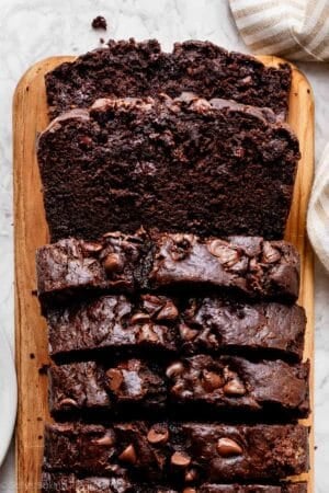 sliced loaf of chocolate banana bread on loaf shaped cutting board.