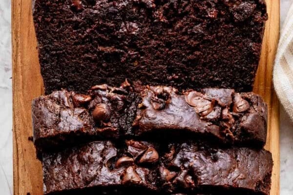 sliced loaf of chocolate banana bread on loaf shaped cutting board.