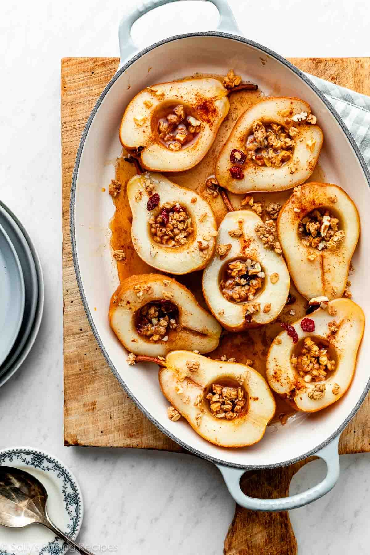 baked pears in blue and white oval baking pan on wooden cutting board.