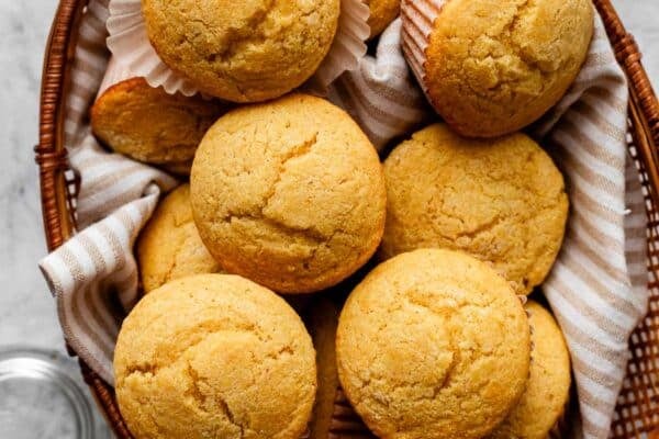 basket of cornbread muffins with beige striped linen.