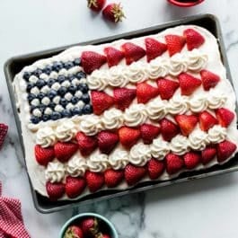 vanilla sheet cake decorated like an American flag with berries and frosting