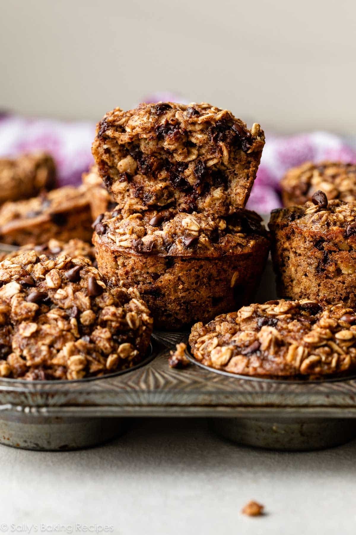 baked chocolate chip oatmeal cup muffins in muffin pan and two stacked on top of eachother.