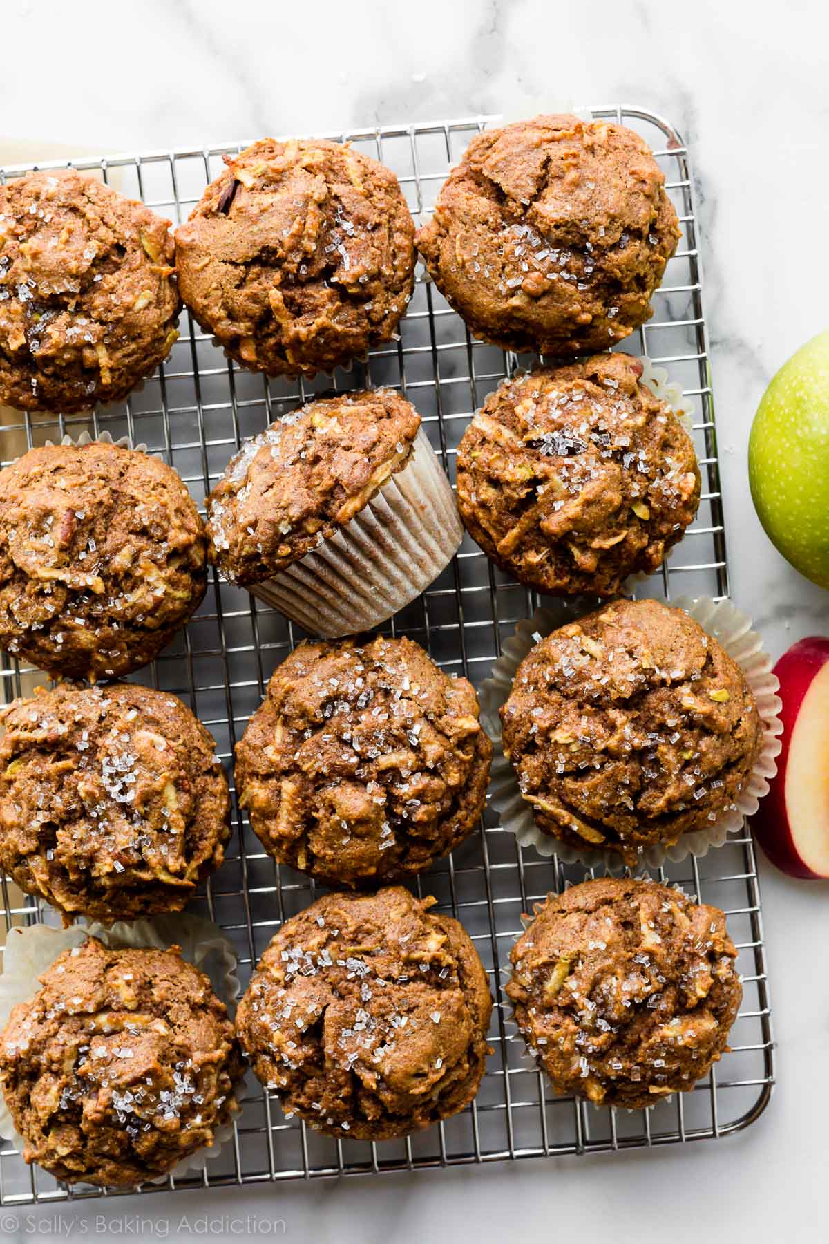 12 healthy apple muffins on wire cooling rack with coarse sugar sprinkled on top of each.