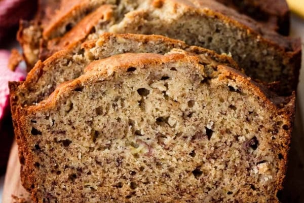 homemade banana bread slices on wooden cutting board.