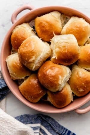 dinner rolls with honey butter topping in pink ceramic pie dish.