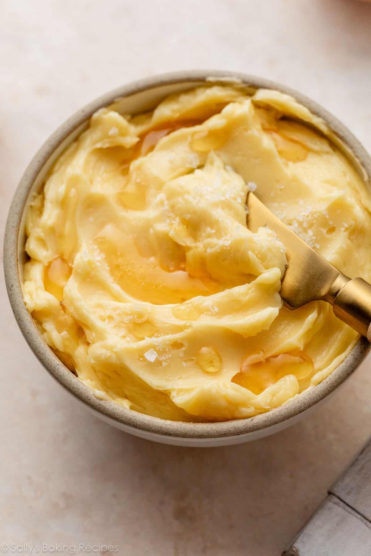 homemade honey butter in bowl with flaky sea salt on top.