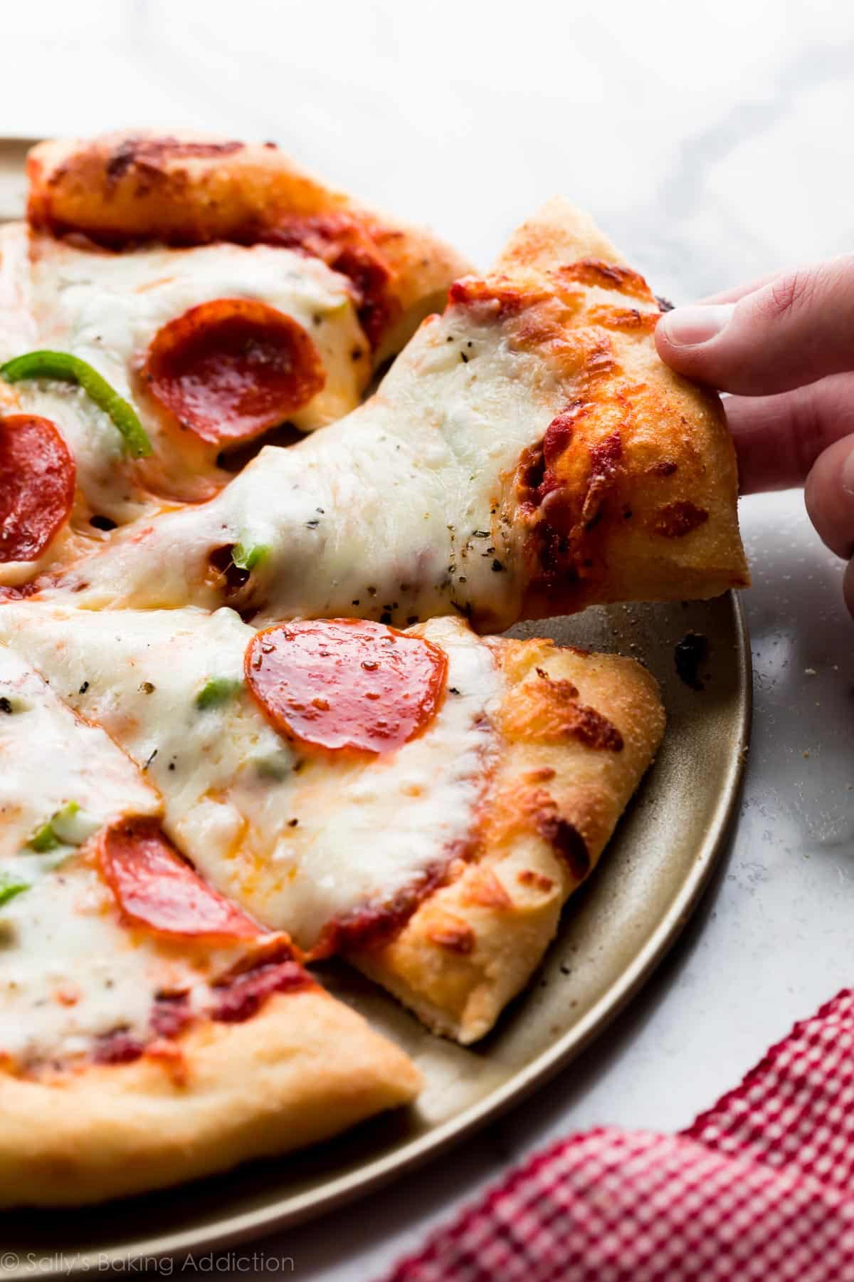 Homemade pizza cut into slices with a piece being removed