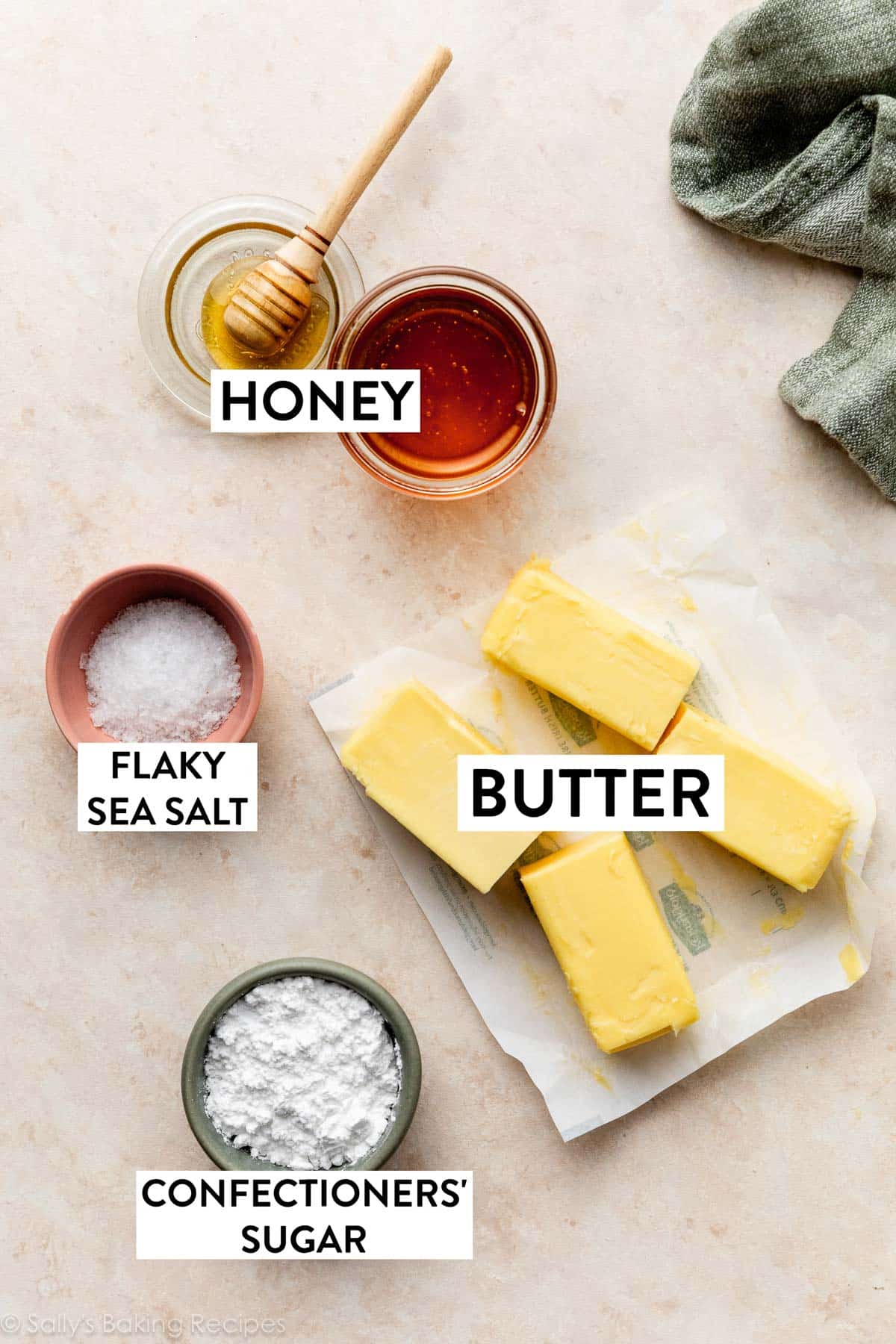 ingredients on beige surface including honey, sea salt, and confectioners' sugar.