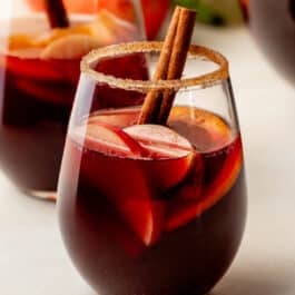 glass of red wine sangria with honeycrisp apples, oranges, and cinnamon stick.