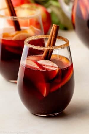 glass of red wine sangria with honeycrisp apples, oranges, and cinnamon stick.