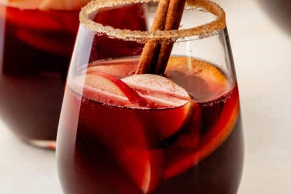 glass of red wine sangria with honeycrisp apples, oranges, and cinnamon stick.