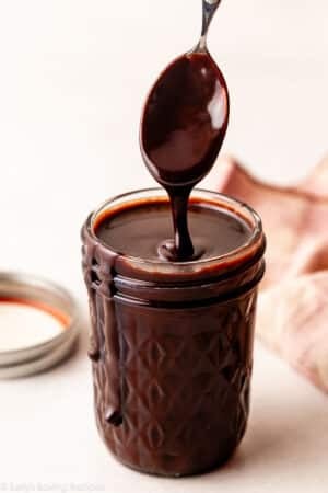 hot fudge sauce being drizzled from spoon into jar.