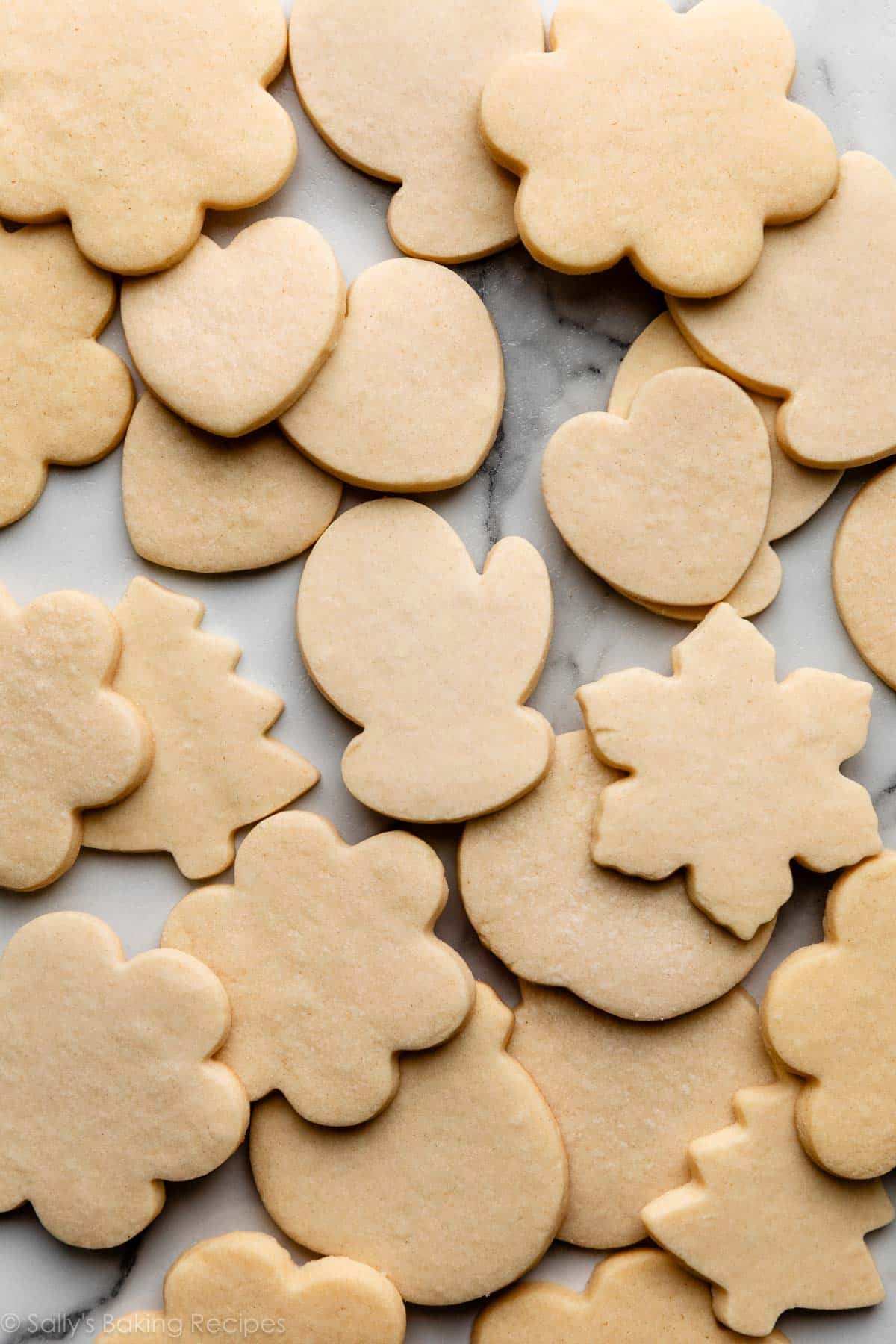 sugar cookies in various shapes and sizes on marble counter.