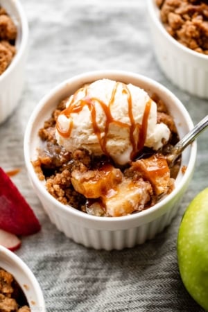 individual apple crumble in ramekin with ice cream and caramel on top