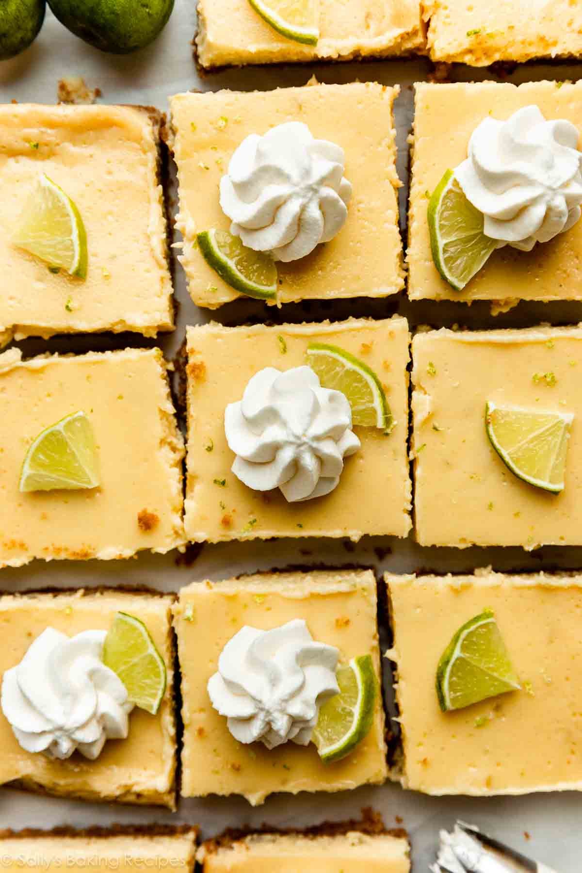 overhead photo of key lime pie bars with lie wedges and whipped cream on top.