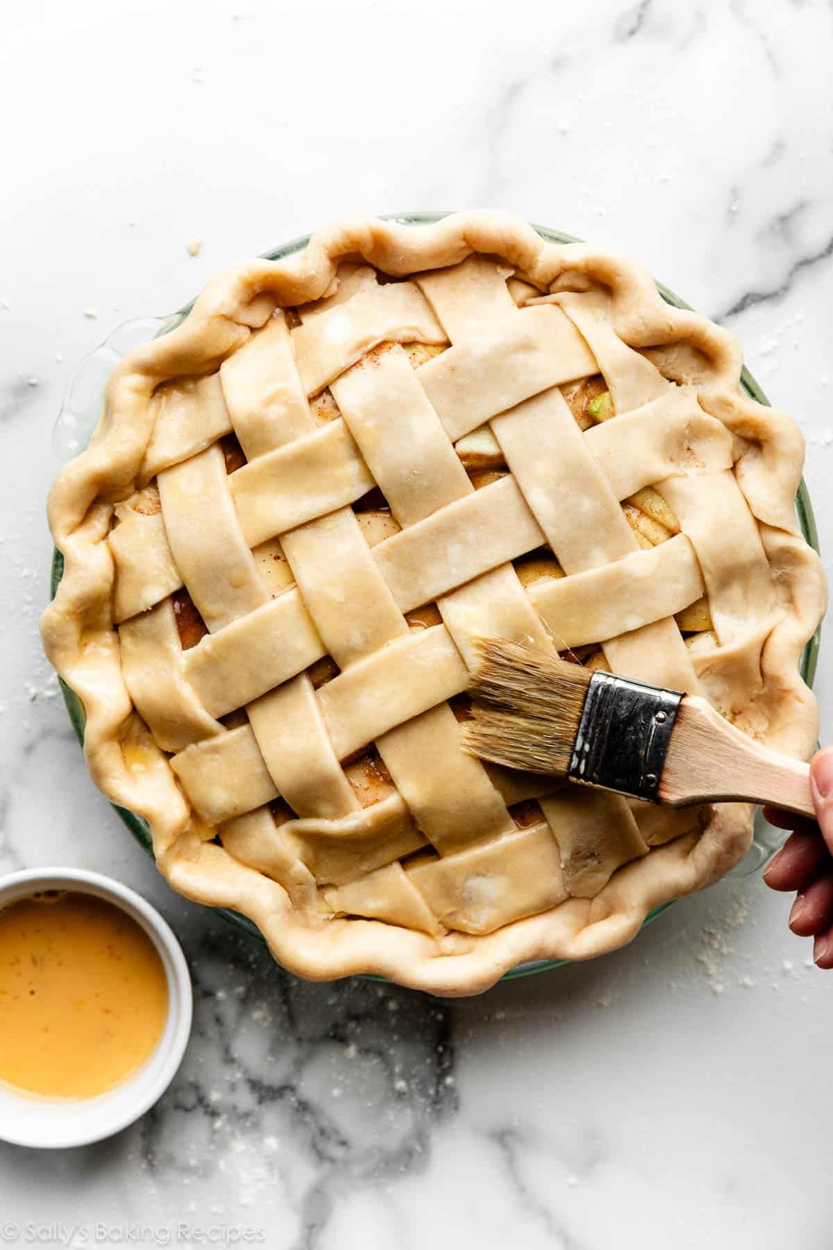 pastry brush shown brushing egg wash on unbaked pie crust.