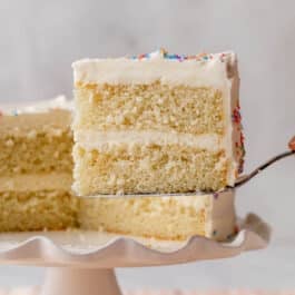 slice of white cake being taken away from cake stand.