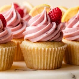 lemon cupcakes with raspberry jam buttercream on marble cake stand.