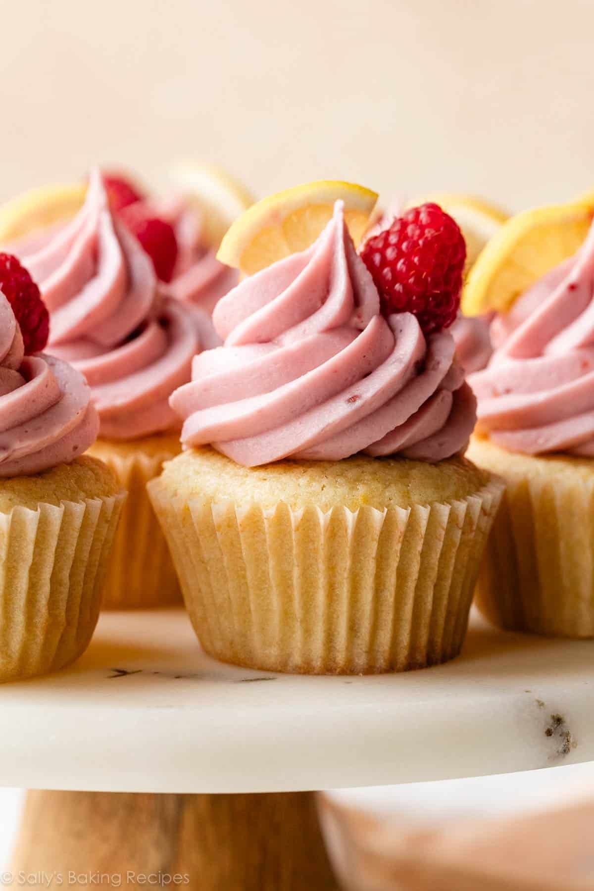 lemon cupcakes with raspberry jam buttercream on marble cake stand.