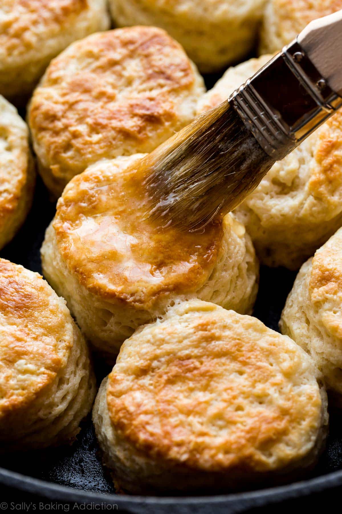 brushing honey butter onto homemade biscuits