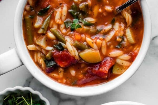 overhead photo of bowls of tomato and broth-based minestrone soup with orzo pasta.