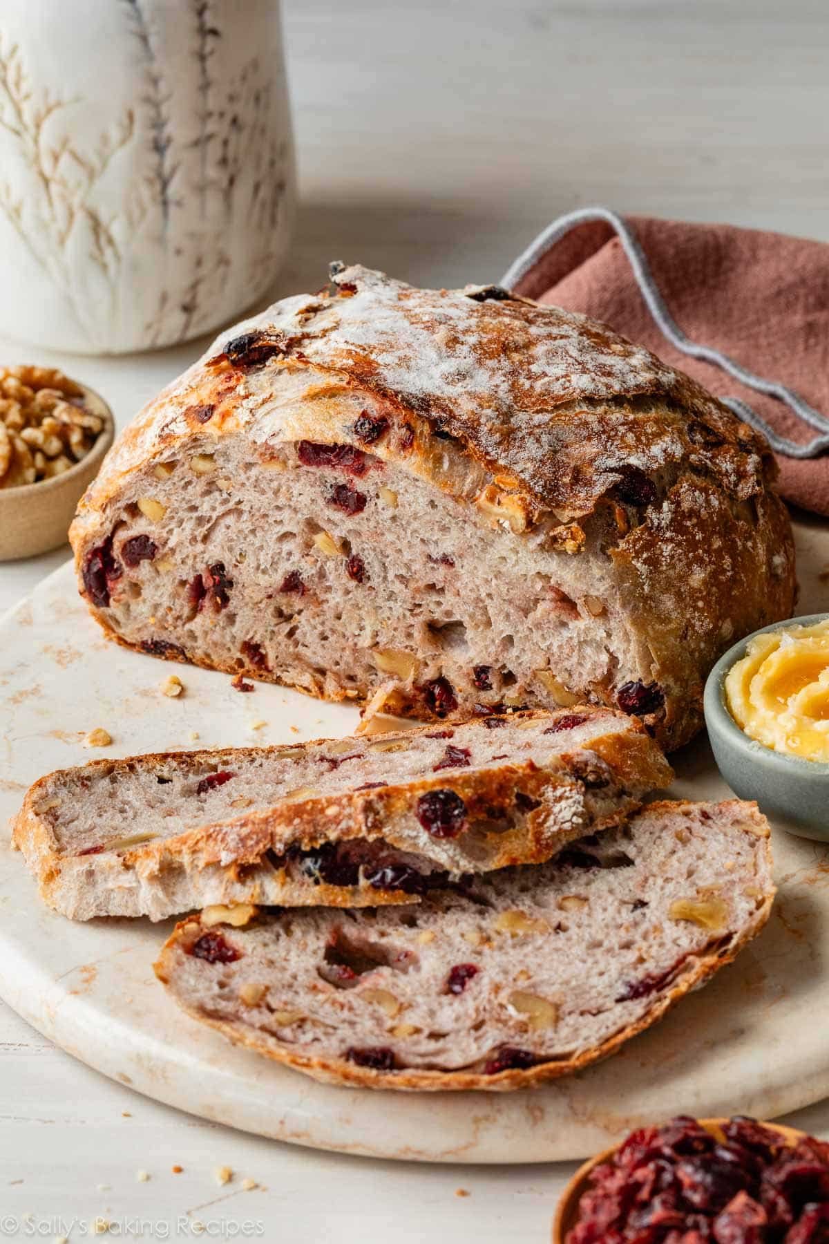 round boule loaf of cranberry nut bread on marble serving tray.