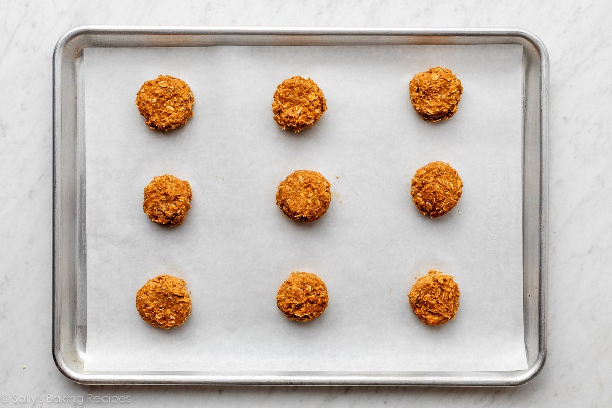 mounds of pumpkin cookie dough on lined baking sheet.